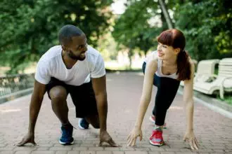 Multiethnic couple in sport clothes on starting line preparing to run in the park