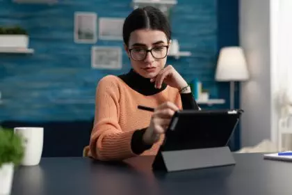 Student with glasses holding stylus touching tablet screen
