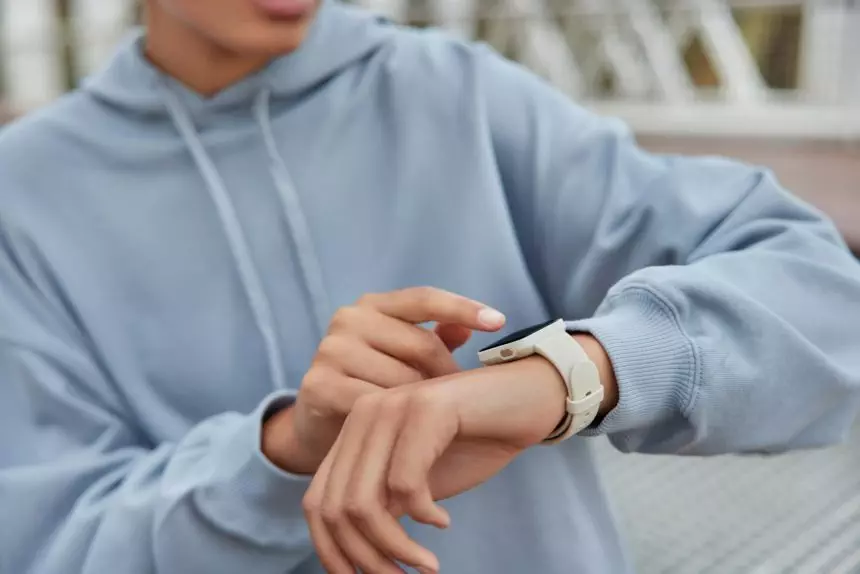 Unrecognizable woman checks results of fitness training on smartwatch uses modern gadget dressed in